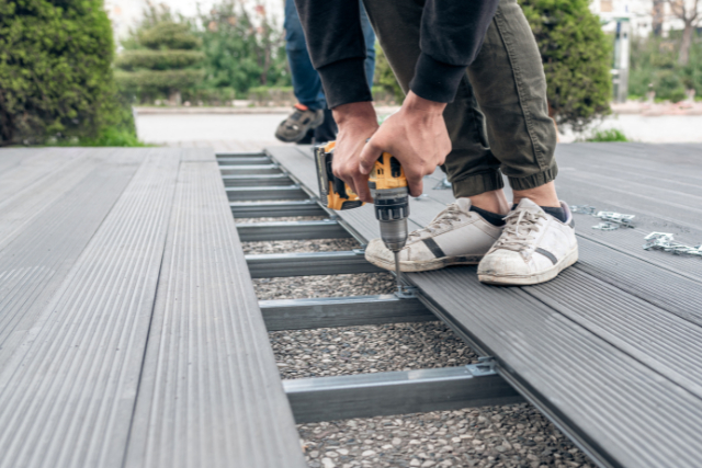 Man assembling composite deck using cordless screwdriver